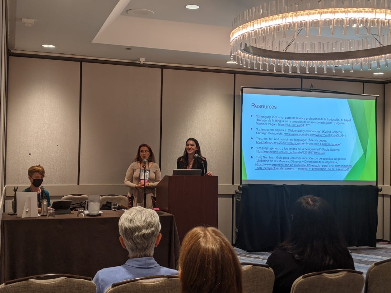 La fotografía muestra a Erika Cosenza y Maitén Vargas frente a un atril en una sala de conferencias. Detrás de ellas, una pantalla muestra la diapositiva final de su presentación «Rethinking Professional Ethics in a Non-Binary Context». A su lado, una mesa con la moderadora. Y frente a ellas, el público.